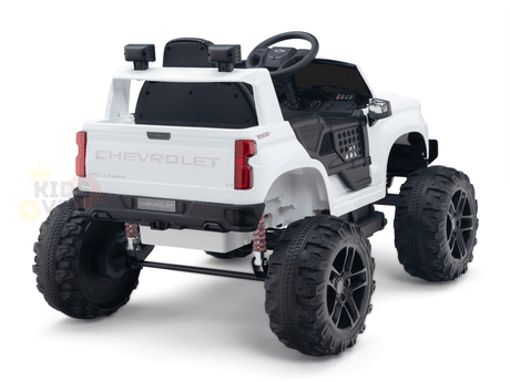 The White 24V Chevrolet Silverado Kids Licensed 1 Seater Ride On Lifted Truck features oversized black wheels, a realistic steering wheel and dashboard, Chevrolet branding on the back, and a robust suspension system for adventurous play.