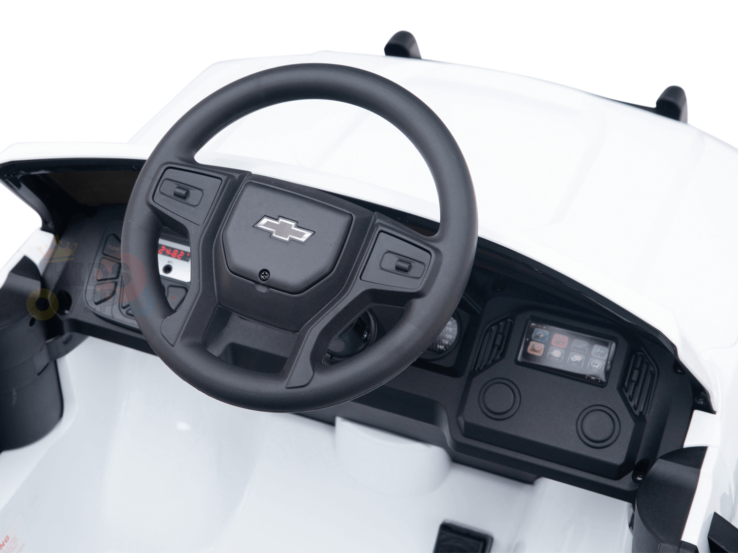 In the White 24V Chevrolet Silverado Ride-On Truck, the miniature dashboard showcases detailed controls and screen displays within a white interior, highlighting a black steering wheel with the Chevy logo—capturing the true essence of this kids licensed product.