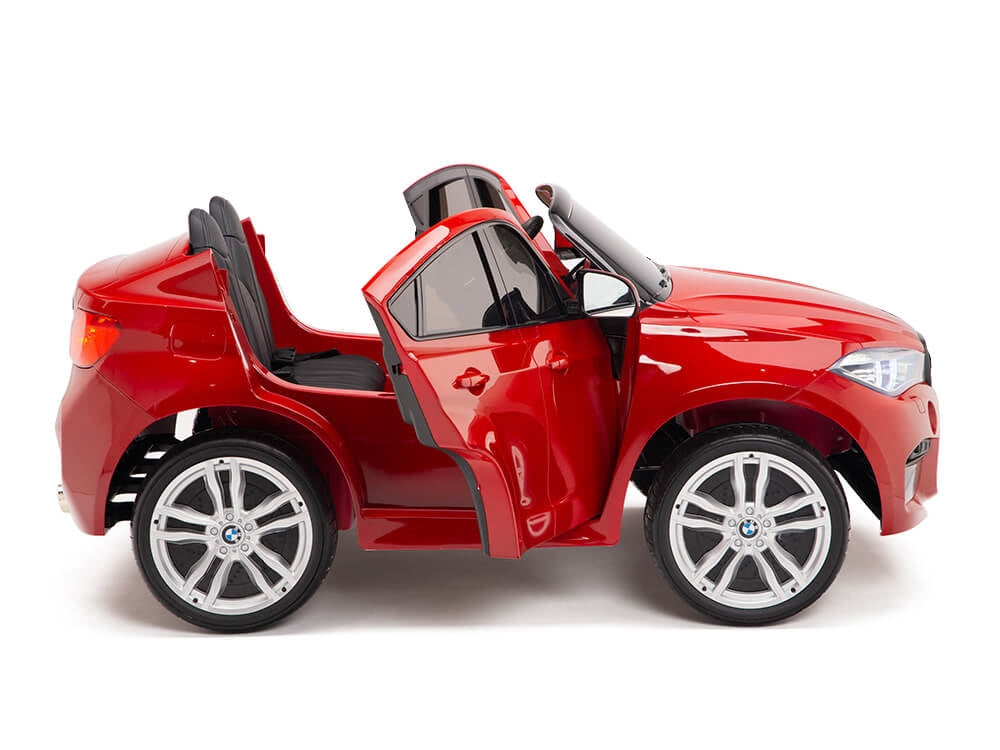 The Red 12V Licensed XXL BMW X6 Ride On Car features a convertible design with open doors, silver wheels, and black seats. Its shown in a side view on a white background, perfect for kids driving adventures with remote control functionality.
