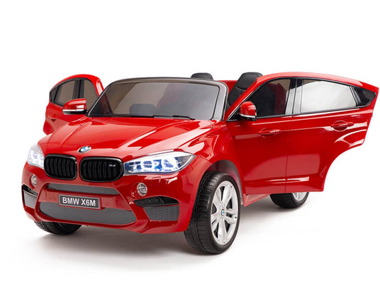 Red BMW X6M kids’ ride-on car with both doors open.