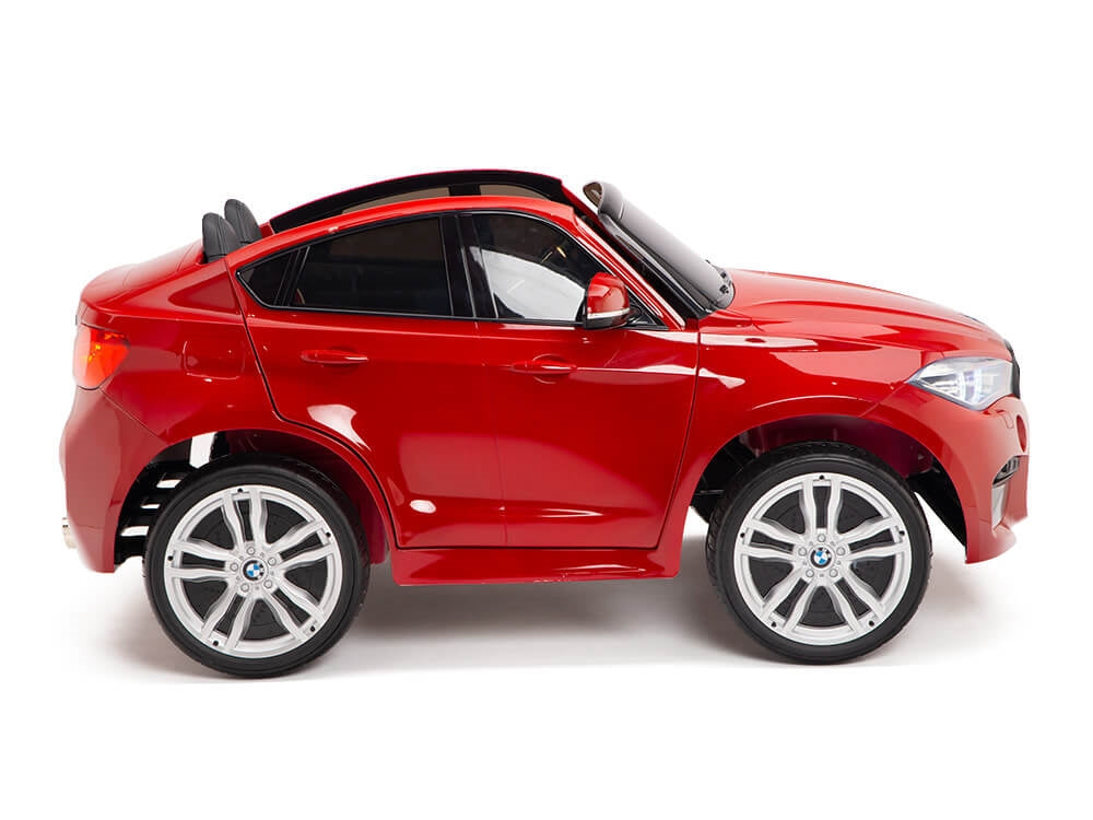 The Red 12V Licensed XXL BMW X6 Ride On Car with Remote Control mimics a luxurious SUV, showcasing black seats and silver wheels. This sleek toy car is displayed in side profile against a pristine white backdrop.