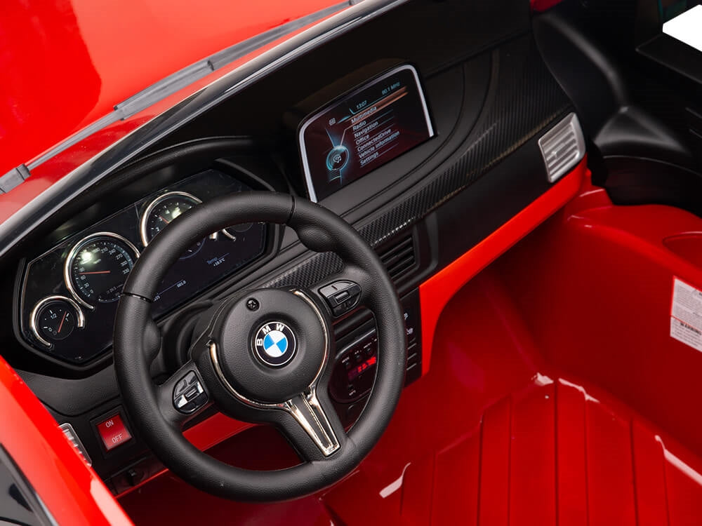 Interior view of the Red 12V Licensed XXL BMW X6 Ride On Car shows a black steering wheel with BMW logo, digital and analog dashboard, and striking black-red detailing. The vibrant red plastic floor captures the sleek allure of this kids ride-on experience.