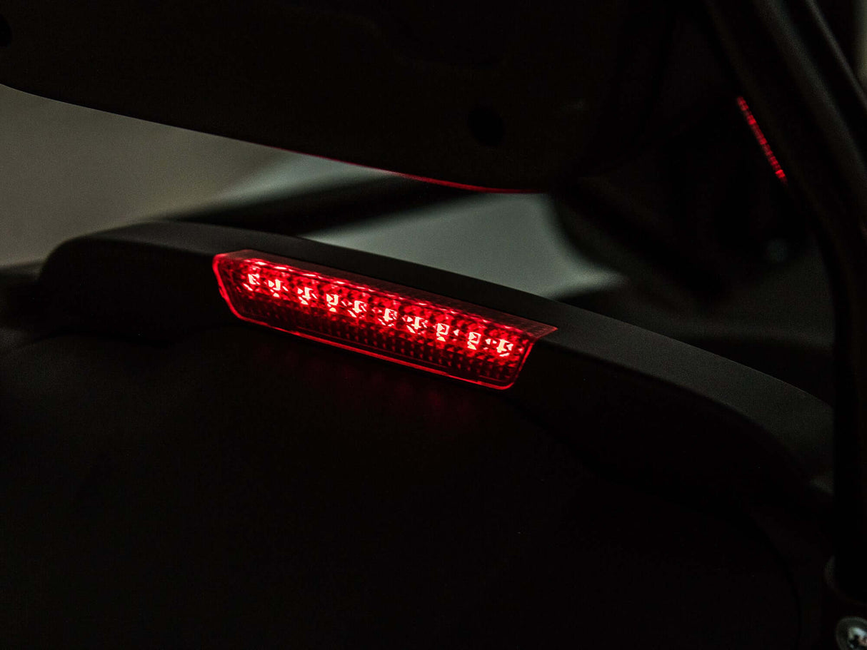 A close-up of an LED taillight in low light shows a sleek black casing with a modern design, reminiscent of the dynamic curves on the Big Kids Powerful 24V Speedster Drifting Go-Kart.