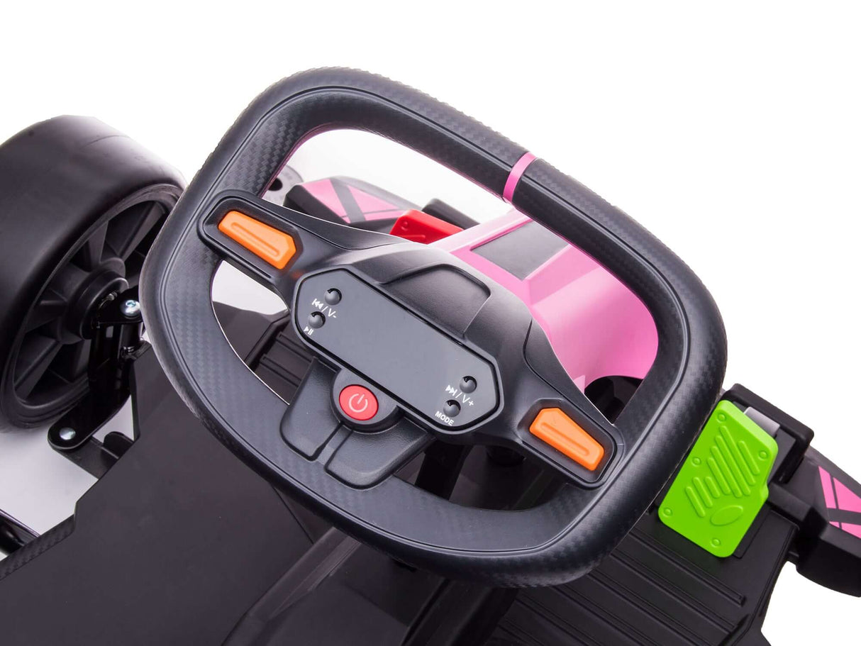 A close-up of a toy cars steering wheel with the sleek design of a Big Kids Powerful 24V Speedster Drifting Go-Kart. The black wheel has orange buttons atop a pink body, highlighted by a red power button in the center and a small green detail on the side panel.