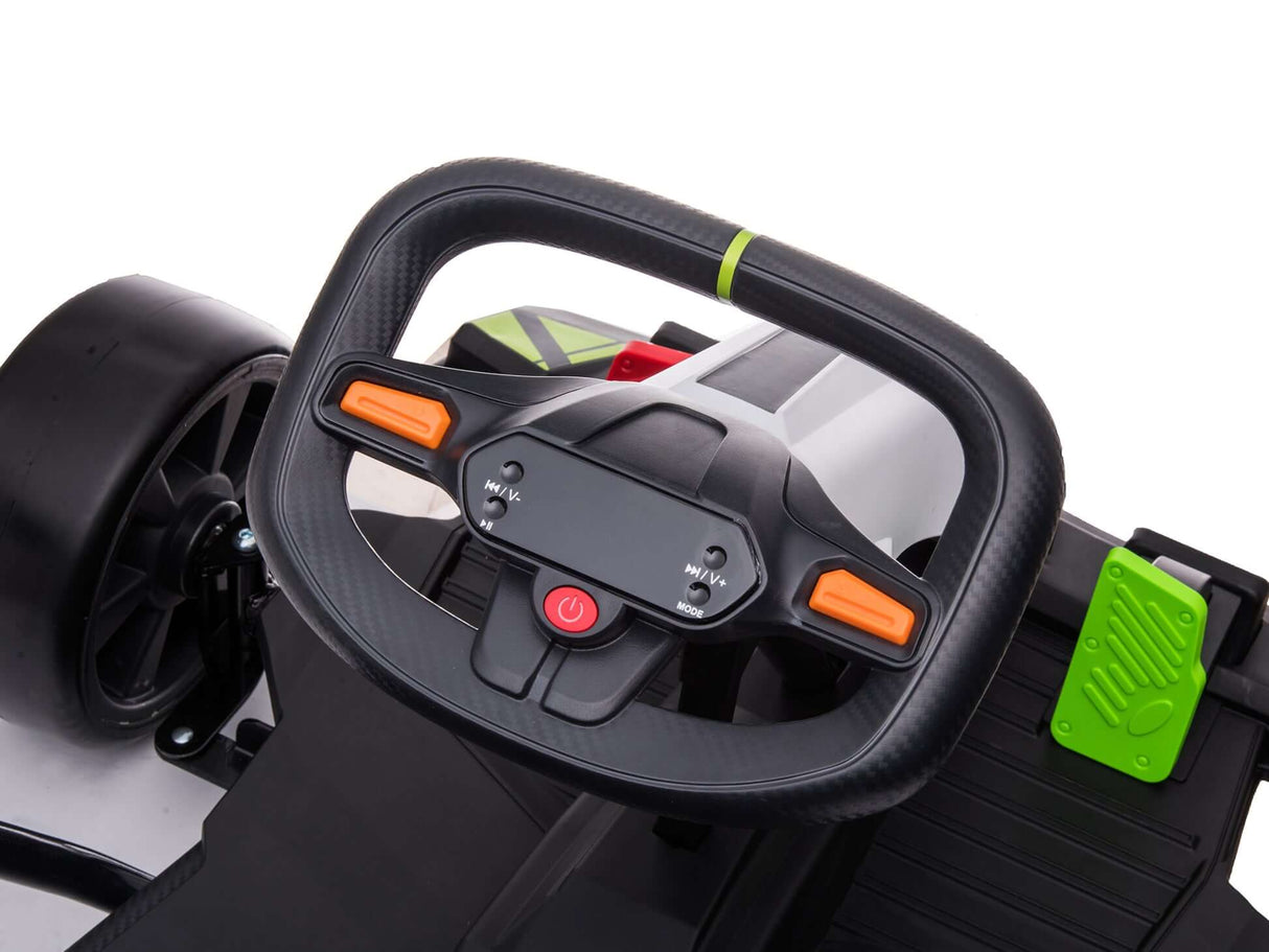 Close-up of the black steering wheel on the Big Kids Powerful 24V Speedster Drifting Go-Kart, featuring two orange buttons and a central red power button; includes an upgraded motor, black seat, textured footrest, and striking green accents on the right side.