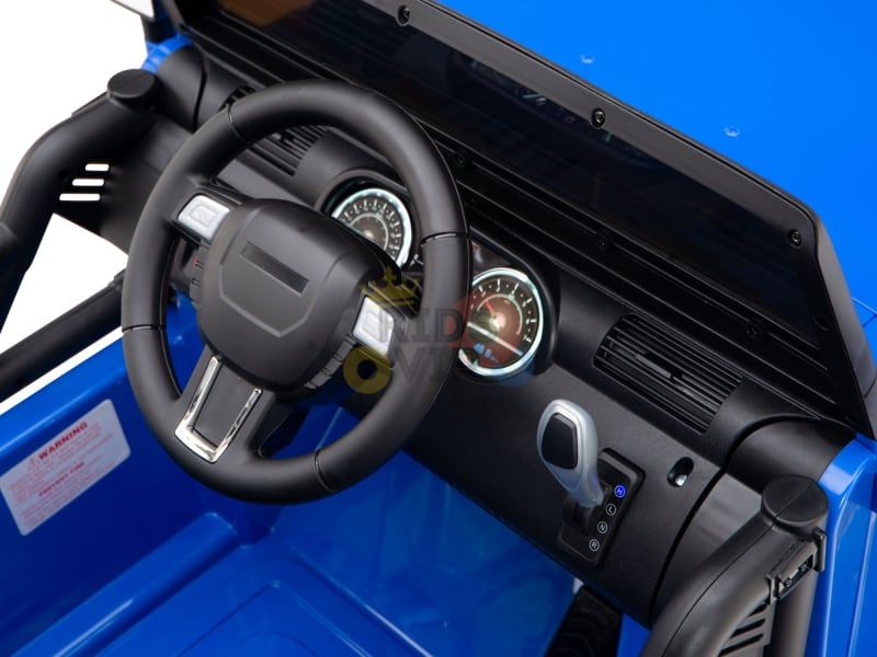 Close-up of the blue 12V Sport Edition Trailcat Big Wheels Kids Ride on Trucks interior, featuring a steering wheel, dashboard with speedometer and tachometer, and gear shifter for a realistic driving experience.