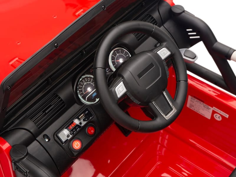 The Red 12V Sport Edition Trailcat Big Wheels Kids Ride on Truck with RC features a detailed dashboard with a black steering wheel, speedometer, and control buttons, emulating a real vehicle. Its oversized wheels enhance the authentic off-road appearance.