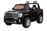 A black toy GMC Sierra ride-on with chrome wheels, side mirrors, orange top lights, and a detailed grille. This 12V/2 seater features an authentic hood and open roof, resembling a real GMC pickup truck.