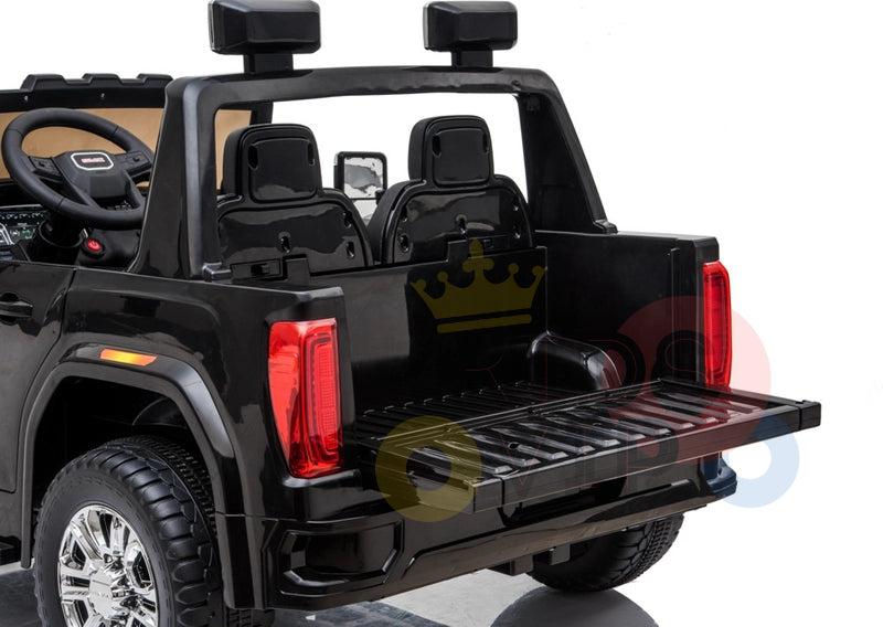 The Black 2x12V Licensed 4WD GMC Sierra Kids Ride On Car features a sleek rear view with two seats, steering wheel, large wheels, open tailgate, realistic details, and side mirrors. Stylish and safe, it includes a parental remote control.