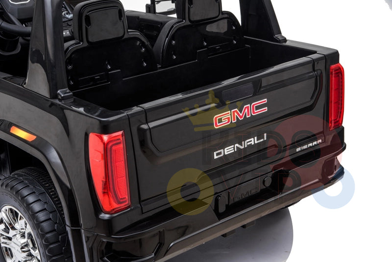 The Black 2x12V Licensed 4WD GMC Sierra Kids Ride On Car with RC features a bright red GMC logo, tailgate, red taillights, black bumper, chrome wheels, and visible seats in the cargo area—ideal for little drivers under parental remote control.