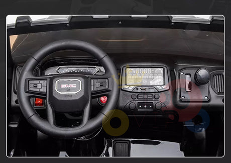 Close-up of a toy car dashboard with a black steering wheel featuring the GMC logo, control buttons, and digital display. The Black 2x12V Licensed 4WD GMC Sierra Kids Ride On Car includes knobs on its glossy black surface, designed for fun and safety with parental remote control.