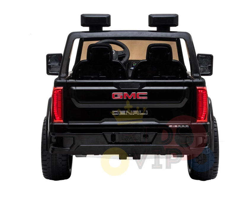 Rear view of a Black 2x12V Licensed 4WD GMC Sierra Kids Ride On Car, showcasing visible interior seating and dashboard. The red GMC logo and Denali badge are on the back. Includes side mirrors, large tires, and a parental remote control for safety.