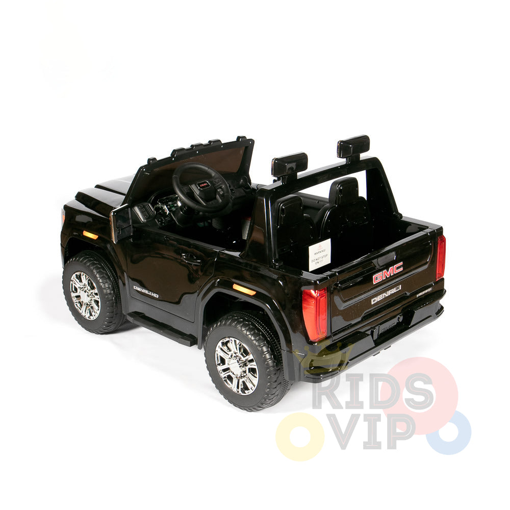 The Black 2x12V Licensed 4WD GMC Sierra Kids Ride On Car with RC features shiny wheels, a detailed interior, branded logos, dual seats, and Parental Remote Control for safety. Its sleek design is highlighted while parked on a white background.