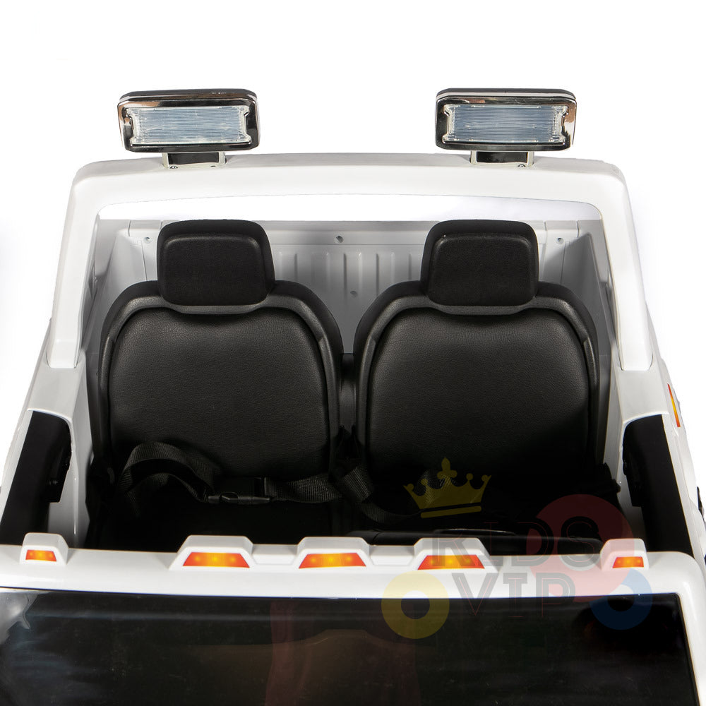 A close-up of the interior of a Black 2x12V Licensed 4WD GMC Sierra Kids Ride On Car shows two black seats and a steering wheel. The rear view highlights roof lights, with logos below and a nearby parental remote control for safety.