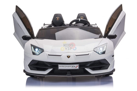 The white 24v Lamborghini SVJ Drifting Kids Ride on Car boasts scissor doors, LED headlights, and detailed front design with Aventador SV on the hood and Kids VIP in the background—perfect for young auto enthusiasts craving luxury.