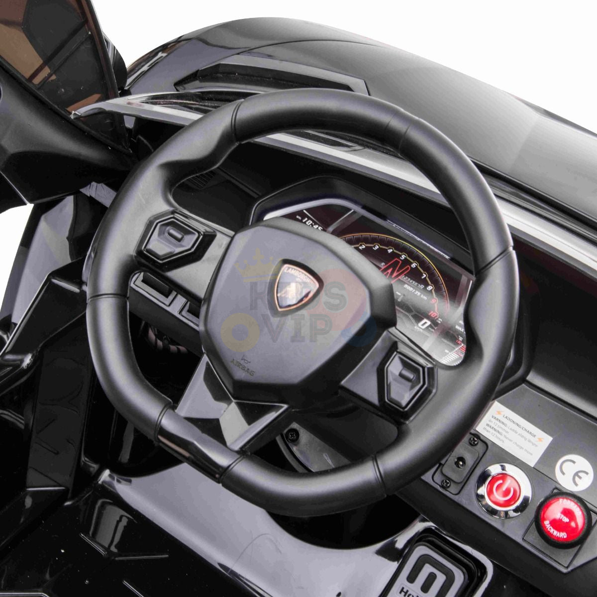 Close-up of a car steering wheel with a modern dashboard in a Black 24V Lamborghini SVJ Ultimate Drifting Car. The digital display shows a compass, accentuated by various buttons and indicators, including ignition and power controls, enhancing the sleek black interior.