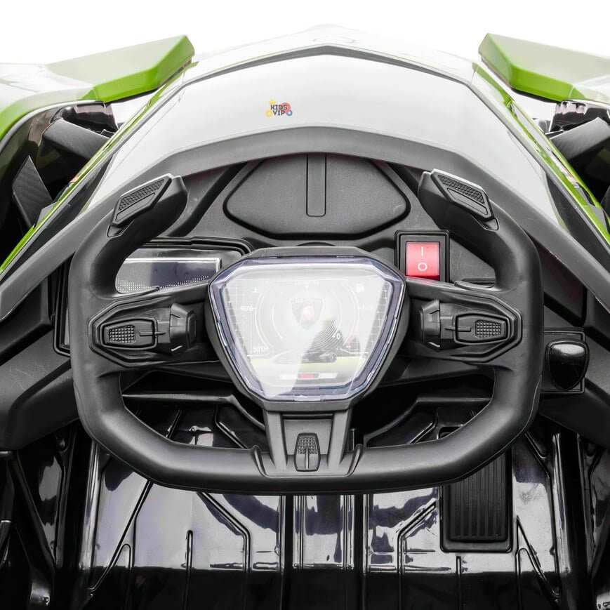 A close-up of the futuristic dashboard in the Green 12V Official Lamborghini Vision GT Kids Ride on Car shows a unique black angular steering wheel with integrated controls. The digital gauges illuminate brilliantly against the gleaming metallic green exterior.