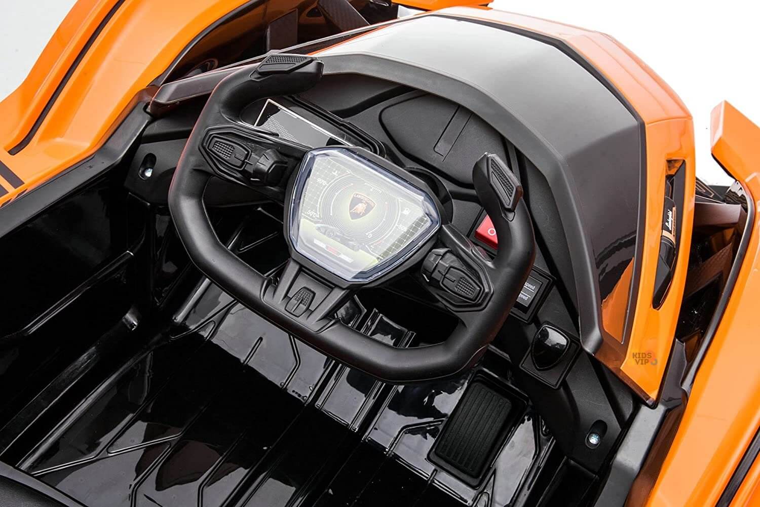 The Orange 12V Official Lamborghini Vision GT Kids Ride-On Car features a black steering wheel with the iconic Lamborghini logo, a sleek digital display, and an orange dashboard, highlighting its angular lines and modern aesthetics that embody innovative artistry.