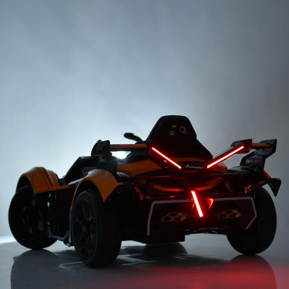 The Orange 12V Official Lamborghini Vision GT Kids Ride-On Car features a sleek orange and black design with red X-shaped LED lights at the rear, showcasing its modern and dynamic style against a neutral background.
