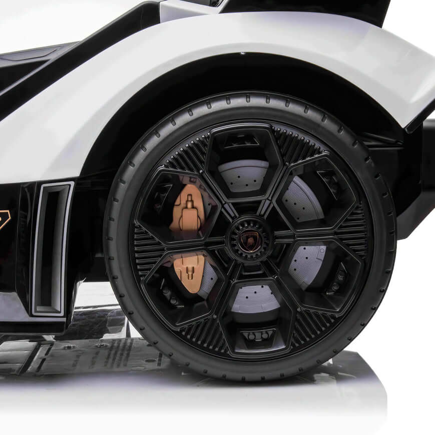 A close-up of a futuristic black wheel with geometric patterns and bronze details on the White 12V Official Lamborghini Vision GT Kids Ride-On Car. The design features hexagons and a sleek, modern look, powered by a 12V battery for an exhilarating experience.