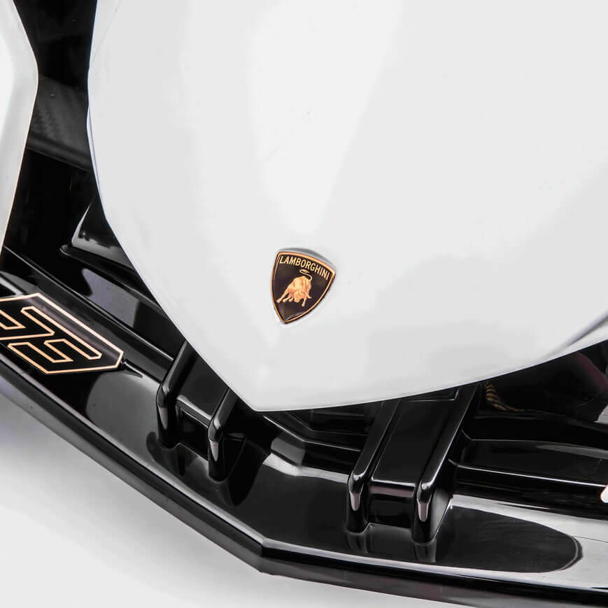 A close-up of the White 12V Official Lamborghini Vision GT Kids Ride-on car showcases its front end with the iconic gold bull logo. Its sleek design and glossy finish echo a real Lamborghini, capturing youthful dreams.