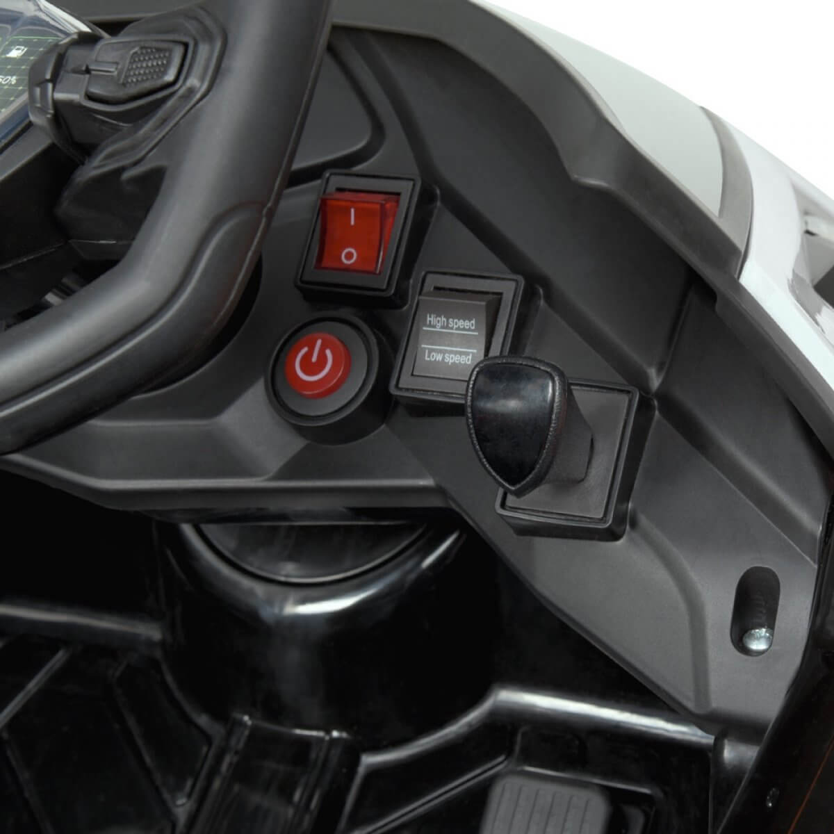 Close-up of the White 12V Official Lamborghini Vision GT Kids Ride-on Car dashboard, featuring a steering wheel, power switch, High speed and Low speed controls, primarily in black with metallic accents and a prominent red button.
