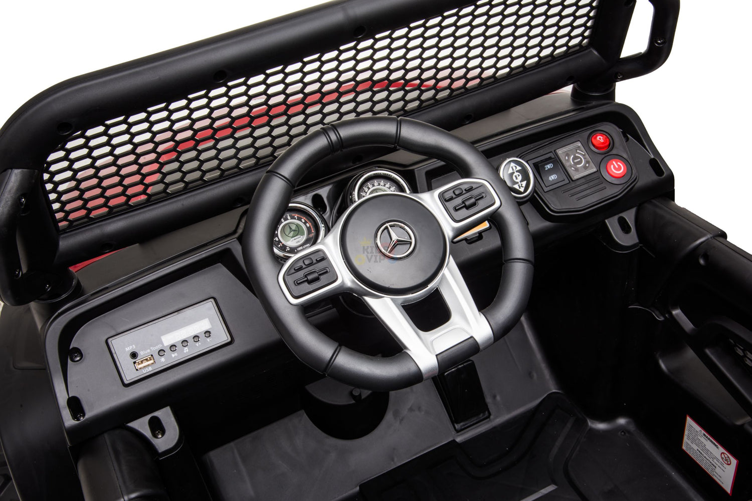 Close-up of the Black Official 12V Mercedes Unimog Junior 4X4 dashboard, featuring a steering wheel with logo, speedometer, control buttons, simulated media player with USB input, power buttons; interior is black with red accents.