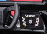 The dashboard of the Futuristic 12V Police Truck Ride On features a checkered steering wheel with a red button, control panel with buttons for radio and USB input, and a display screen showing 108.8, enhancing its high-tech appeal.