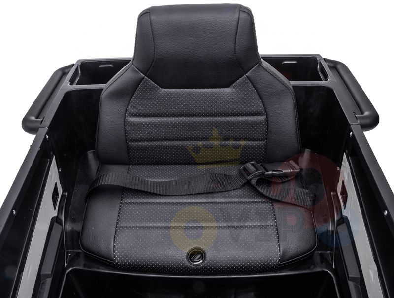 The image shows a black seat in a sleek plastic enclosure of the Futuristic 12V Police Truck Ride On for Kids, featuring a textured backrest and cushion with a harness-style strap, echoing design elements from emergency vehicles.