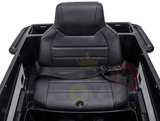 The image shows a black seat in a sleek plastic enclosure of the Futuristic 12V Police Truck Ride On for Kids, featuring a textured backrest and cushion with a harness-style strap, echoing design elements from emergency vehicles.
