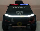 The Futuristic 12V Police Truck Ride On for Kids and Toddlers, part of the Futuristic Series, features POLICE on the windshield. Its sleek design is enhanced by red and blue roof lights and a striking front shield emblem.