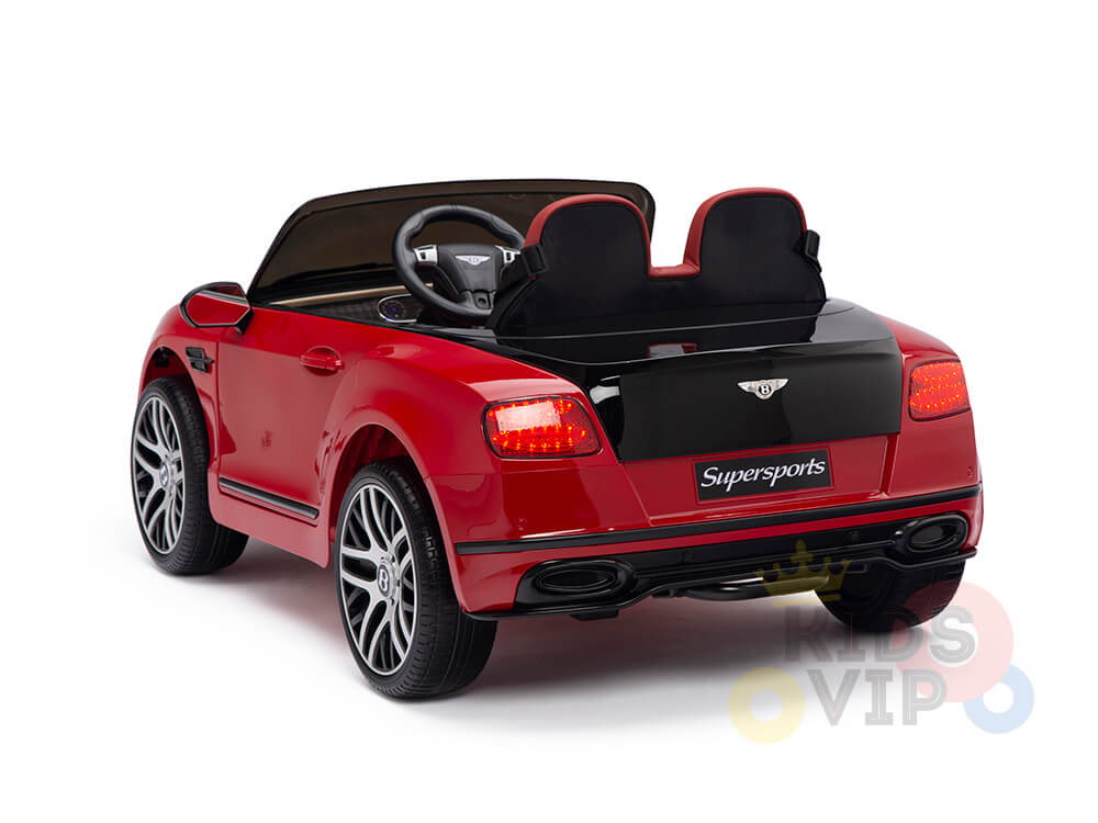 The Red 12V Bentley GTC Kids Licensed Ride On Car boasts a convertible sports car design with black seats, lit taillights, and Supersports on the rear. Photographed from behind at an angle, it features a steering wheel for an authentic driving experience.