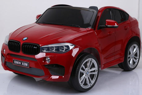 The Red 12V Licensed XXL BMW X6 Ride On Car With Remote Control boasts detailed styling with a prominent front grille, sleek headlights, and five-spoke alloy wheels, all finished in a shiny red against a plain white backdrop.