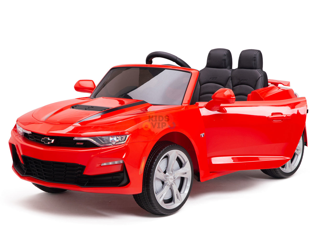 The Red 12V Official Sport Chevrolet Camaro Kids Ride-on Car features two black seats, headlights, mirrors, a small steering wheel, shiny silver wheels, and a front grille logo. This convertible-style car is thrilling for kids as it’s powered by a 12V battery.