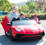 A woman and child joyfully sit in a Red 24V/180W Lamborghini SV Limited XXL Edition ride-on, doors open, resembling a sports car. They enjoy Kids VIP fun outdoors on a sunny day, surrounded by greenery and trees, experiencing the thrill at speeds up to 10 MPH.